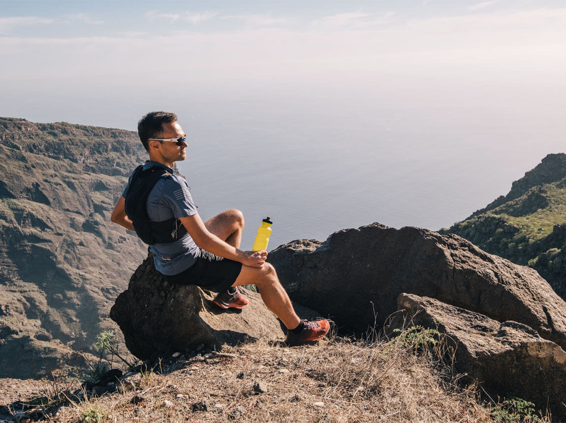 muž s izotonickým napojem v horách